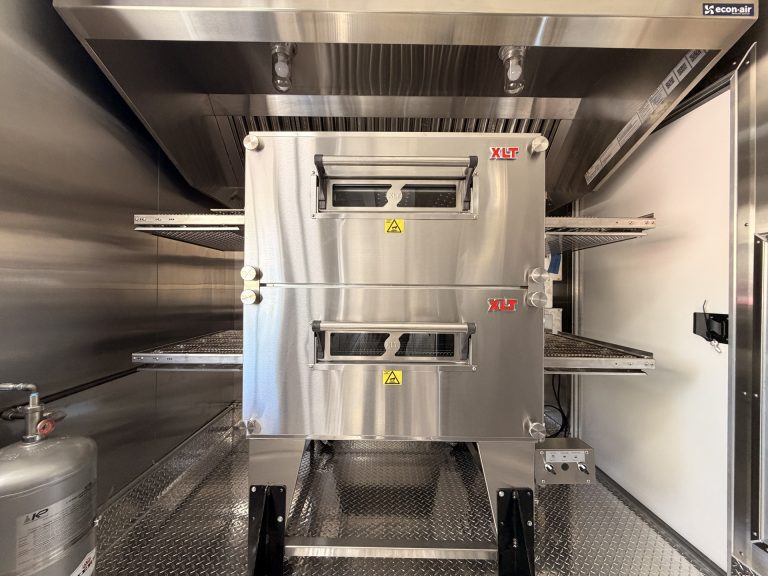 pizza food trailer interior with commercial refrigeration, stainless steel prep surfaces, and kitchen equipment