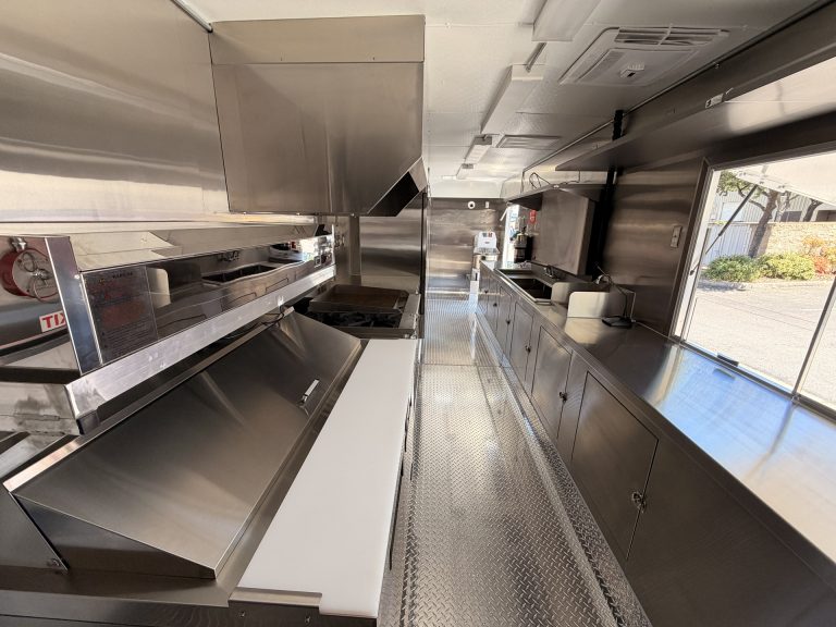 mobile pizza kitchen interior with stainless steel prep surfaces, refrigeration, and cooking equipment
