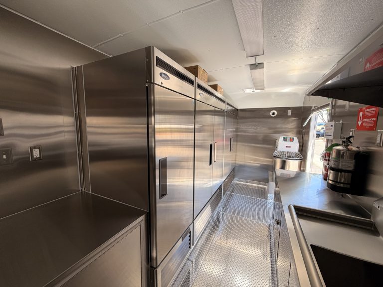 commercial pizza trailer interior with stainless steel prep counters, refrigeration, shelving, and service area