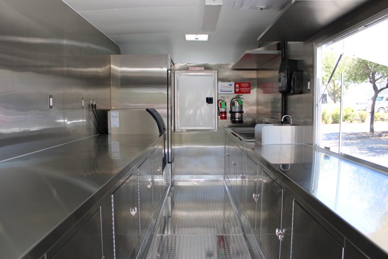 School food trailer interior with stainless steel preparation counters, sinks, and storage