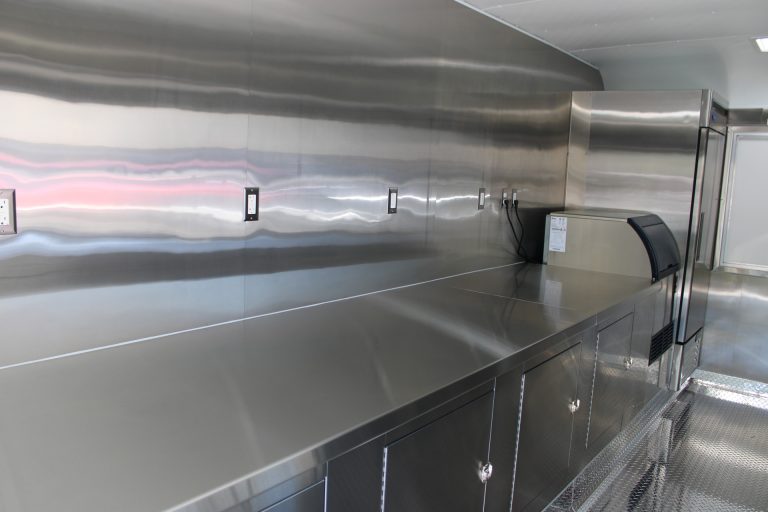 Stainless steel preparation counter with electrical outlets and lower storage inside the school food trailer