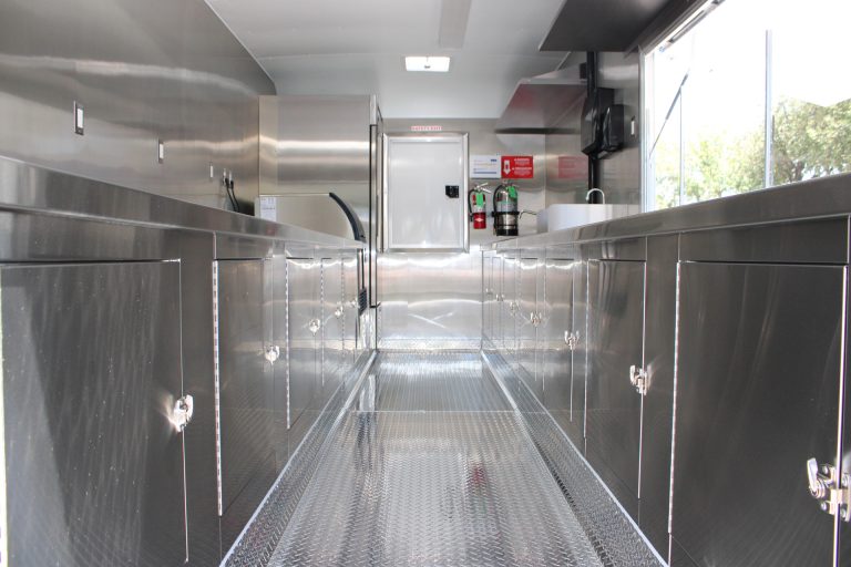 Wide interior view of the 18-ft school food trailer with stainless steel counters and central aisle